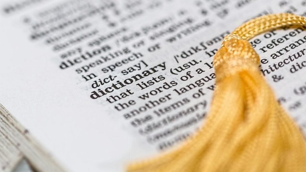 Close-up image of a dictionary page focused on the word 'dictionary' with a yellow tassel.