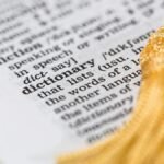 Close-up image of a dictionary page focused on the word 'dictionary' with a yellow tassel.