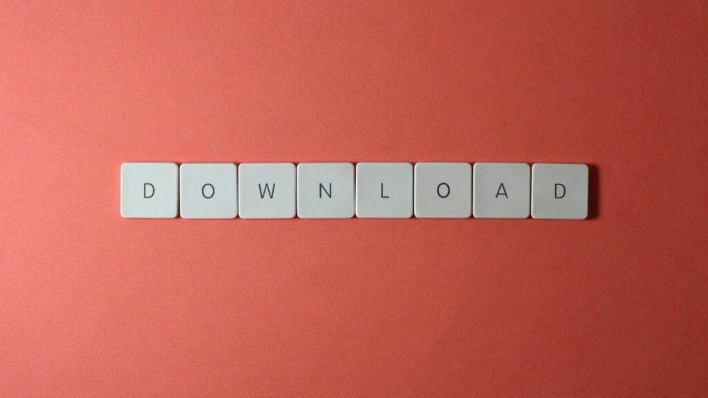 Minimalist photo of keyboard tiles spelling 'DOWNLOAD' on a red background.
