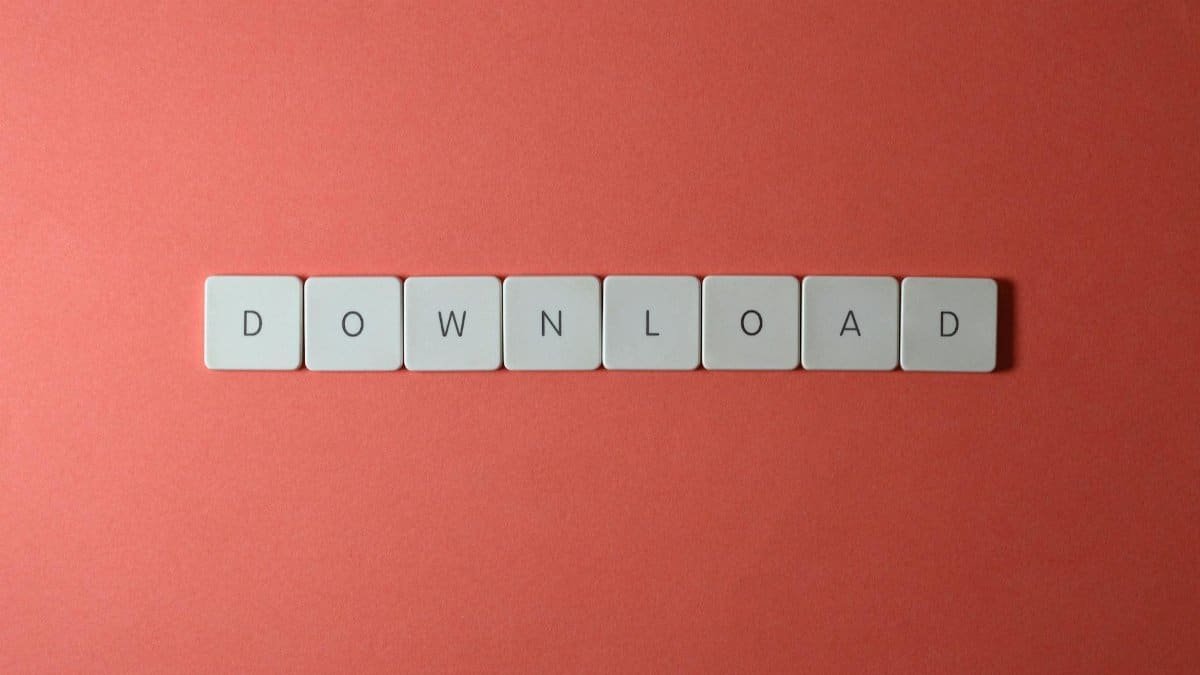 Minimalist photo of keyboard tiles spelling 'DOWNLOAD' on a red background.