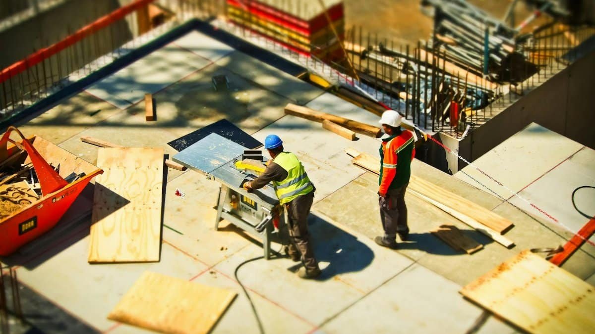 Construction workers engaging in tasks at an outdoor building site with safety hats and equipment.