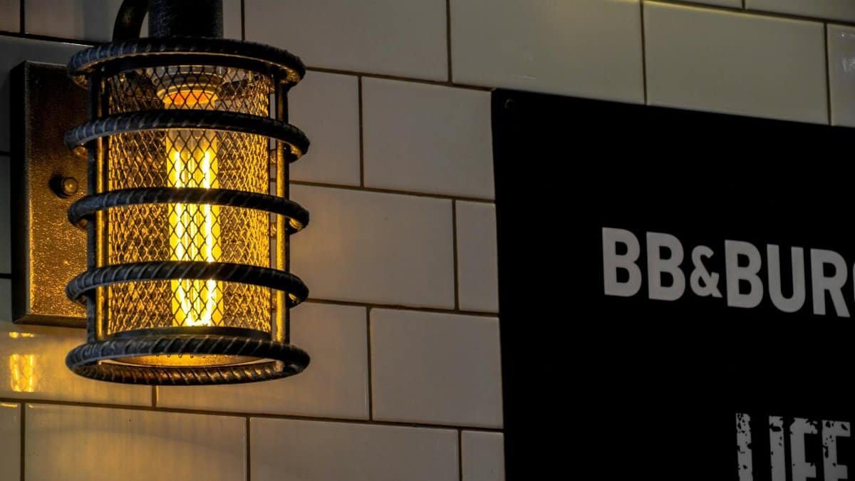 Warmly lit industrial cage lamp against a tiled wall, perfect for cozy indoor environments.