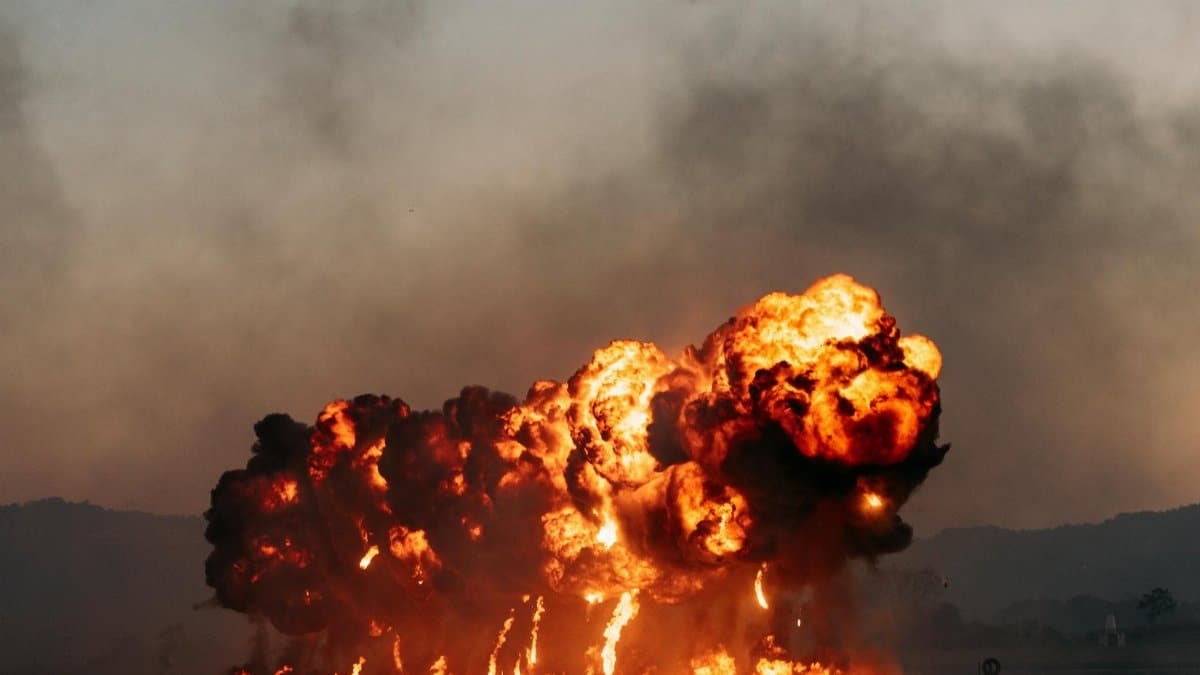 A powerful explosion with intense flames and smoke in an open field during dusk, creating a dramatic scene.