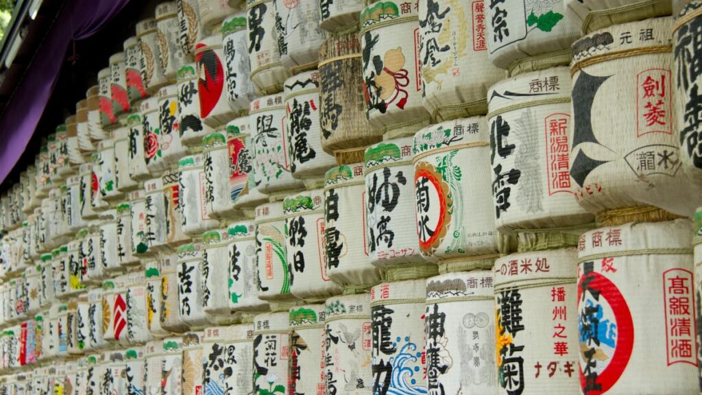 Traditional Japanese sake barrels with vibrant art displayed on shelves in a cultural exhibit.