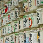 Traditional Japanese sake barrels with vibrant art displayed on shelves in a cultural exhibit.