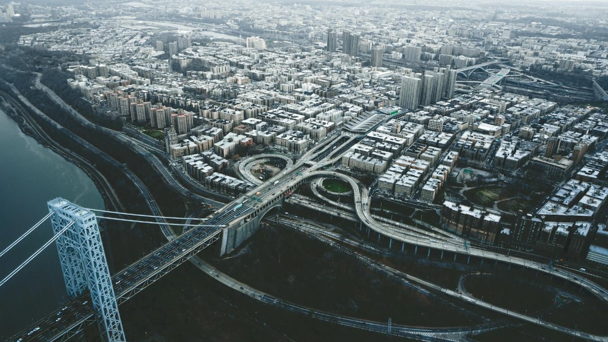 Drone view of George Washington Bridge crossing river and connecting districts of New York City against cloudy sky