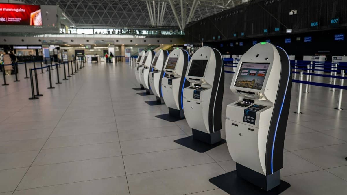 Wide view of an airport terminal in Zagreb featuring self-service check-in kiosks.