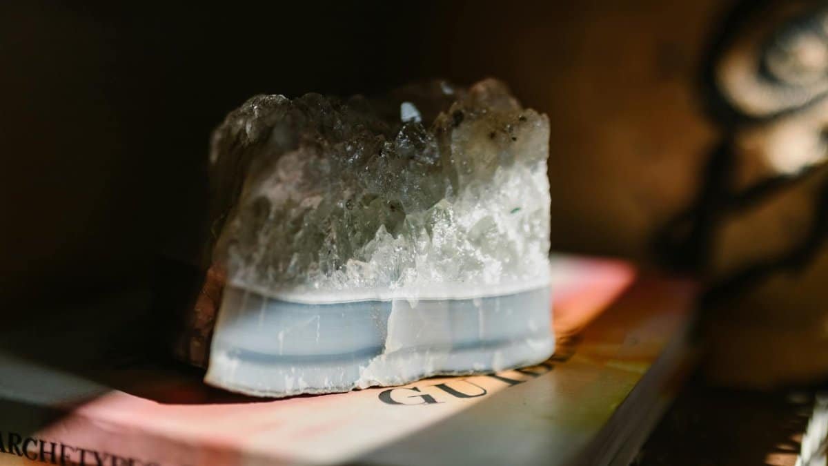 A beautiful crystal stone resting on a book, illuminated by soft sunlight, creating a serene atmosphere.