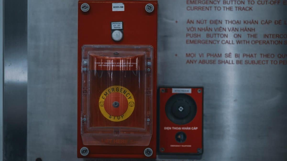 Close-up of an emergency stop button with warning text on an industrial panel.
