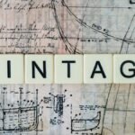 The word 'VINTAGE' on tiles over an old nautical blueprint design.