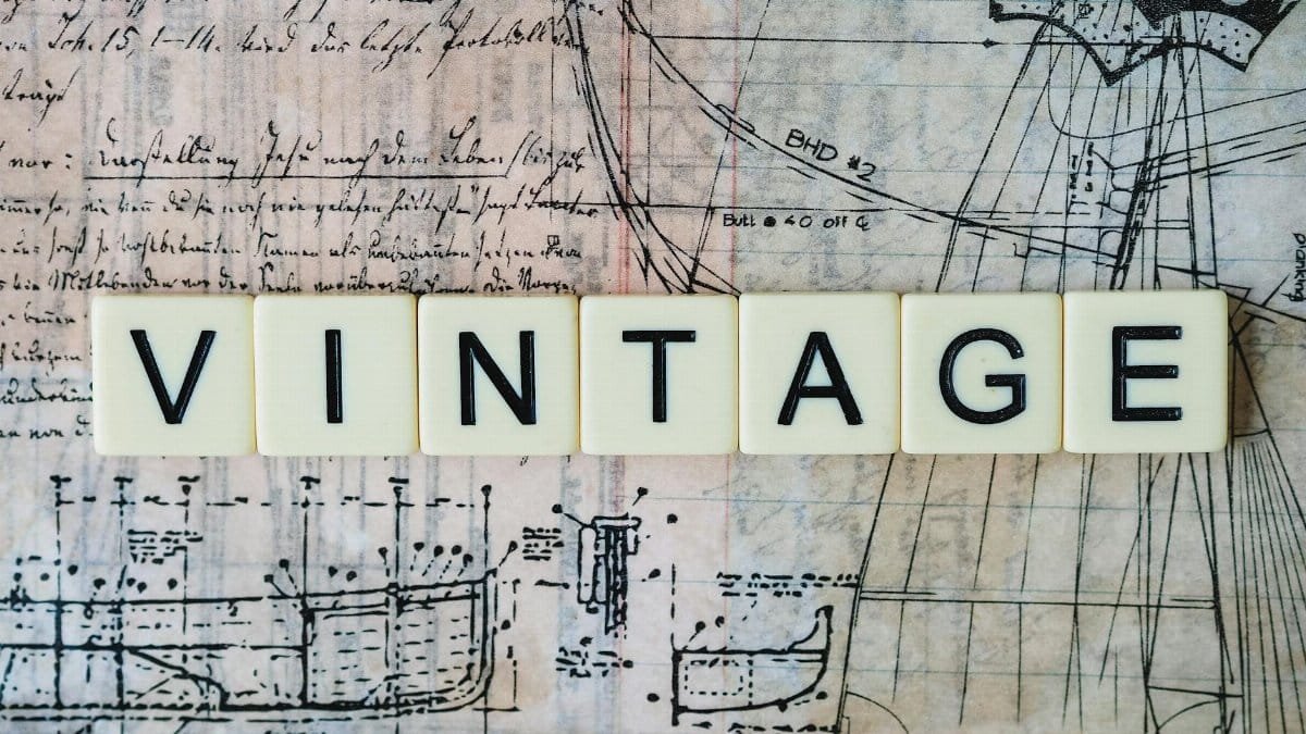 The word 'VINTAGE' on tiles over an old nautical blueprint design.