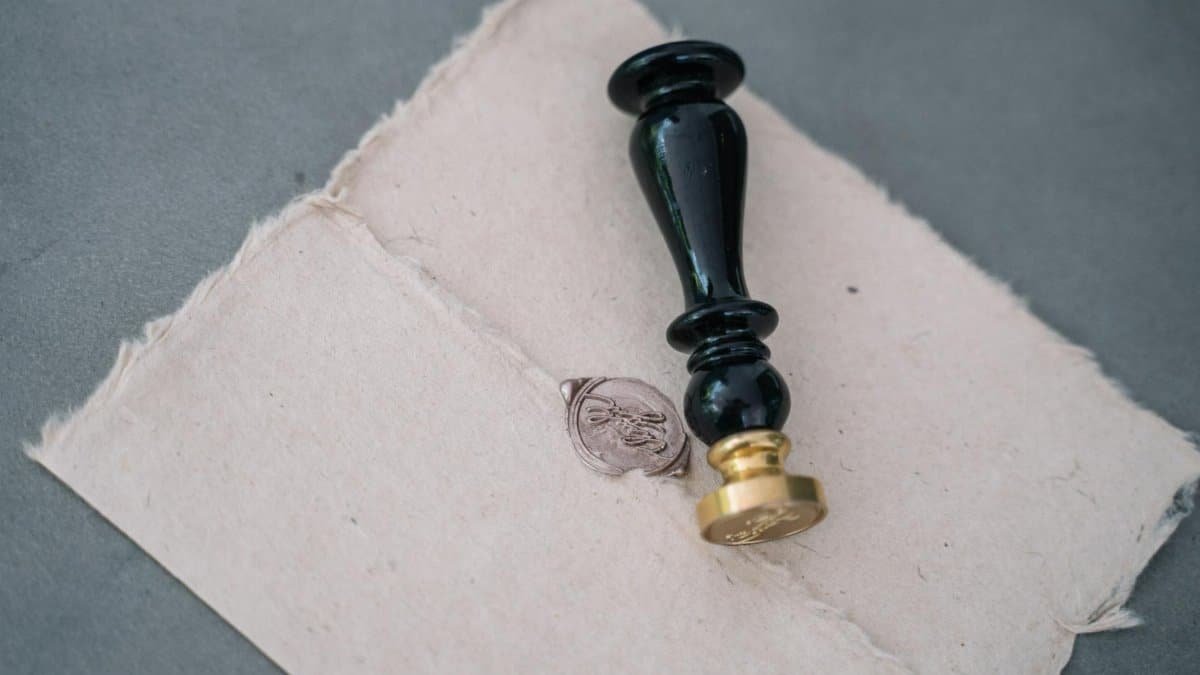 Close-up of a vintage wax seal on a rustic paper envelope with a black sealing stamp.