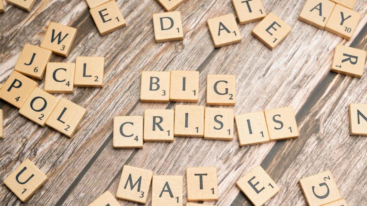 Wooden tiles forming the words 'Big Crisis' on a wooden background.