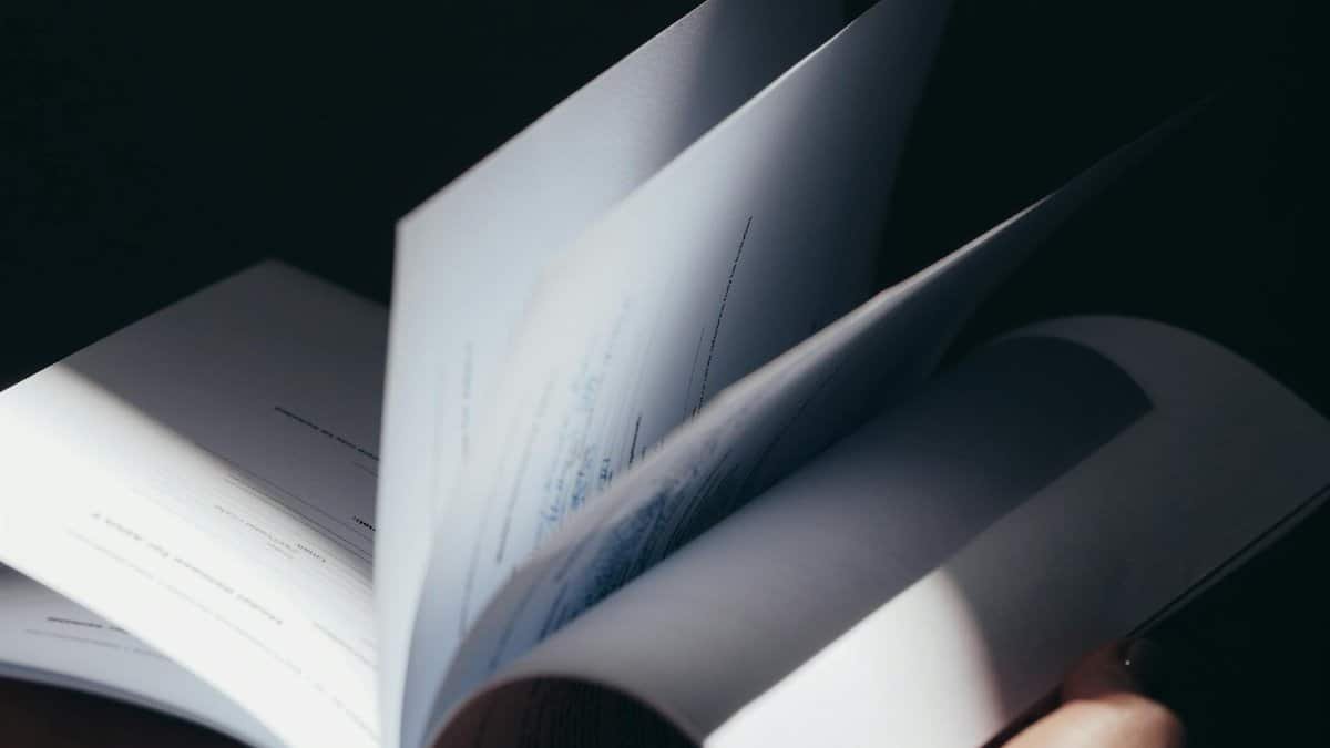 Dramatic close-up of flipping book pages in moody lighting, emphasizing texture and motion.