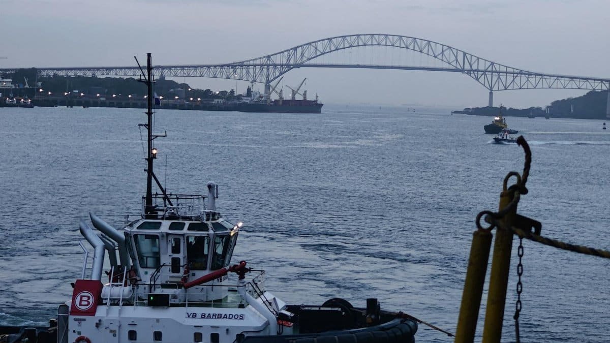 A tugboat sails near the Bridge of the Americas in Cristóbal, Panama at dusk.