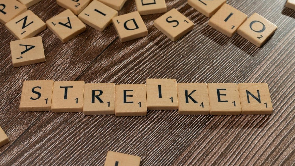 Wooden Scrabble tiles forming the word 'STREIKEN' on a textured surface, indicating a strike theme.