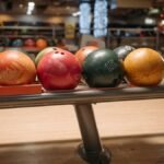 A vibrant collection of bowling balls on a return rack in an indoor bowling alley setting.