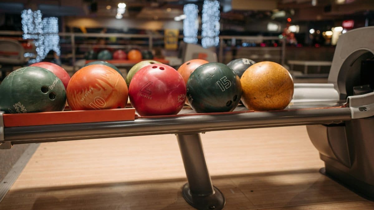 A vibrant collection of bowling balls on a return rack in an indoor bowling alley setting.