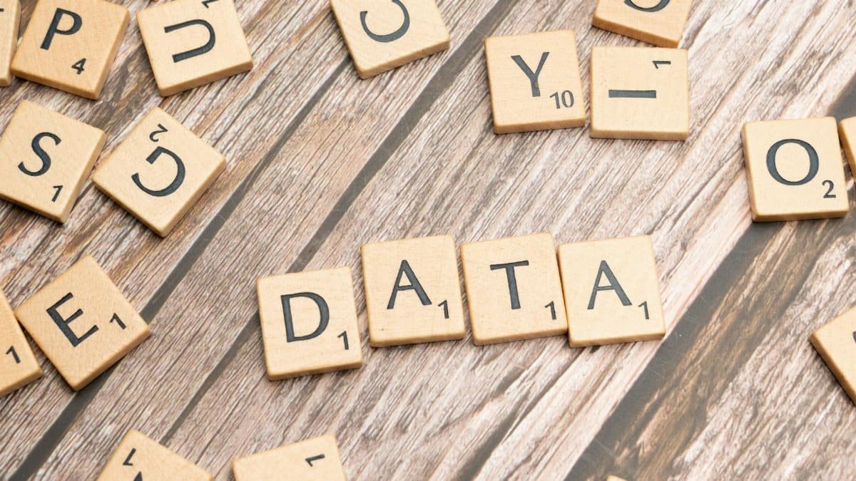 Wooden letter tiles spelling 'DATA' on a wood textured surface, symbolizing data concepts.