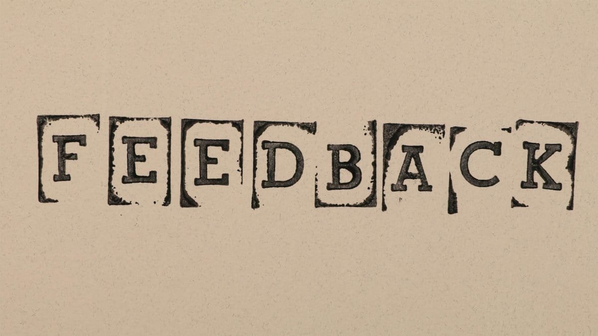Vintage-style stamped letters spelling 'Feedback' on textured paper background.