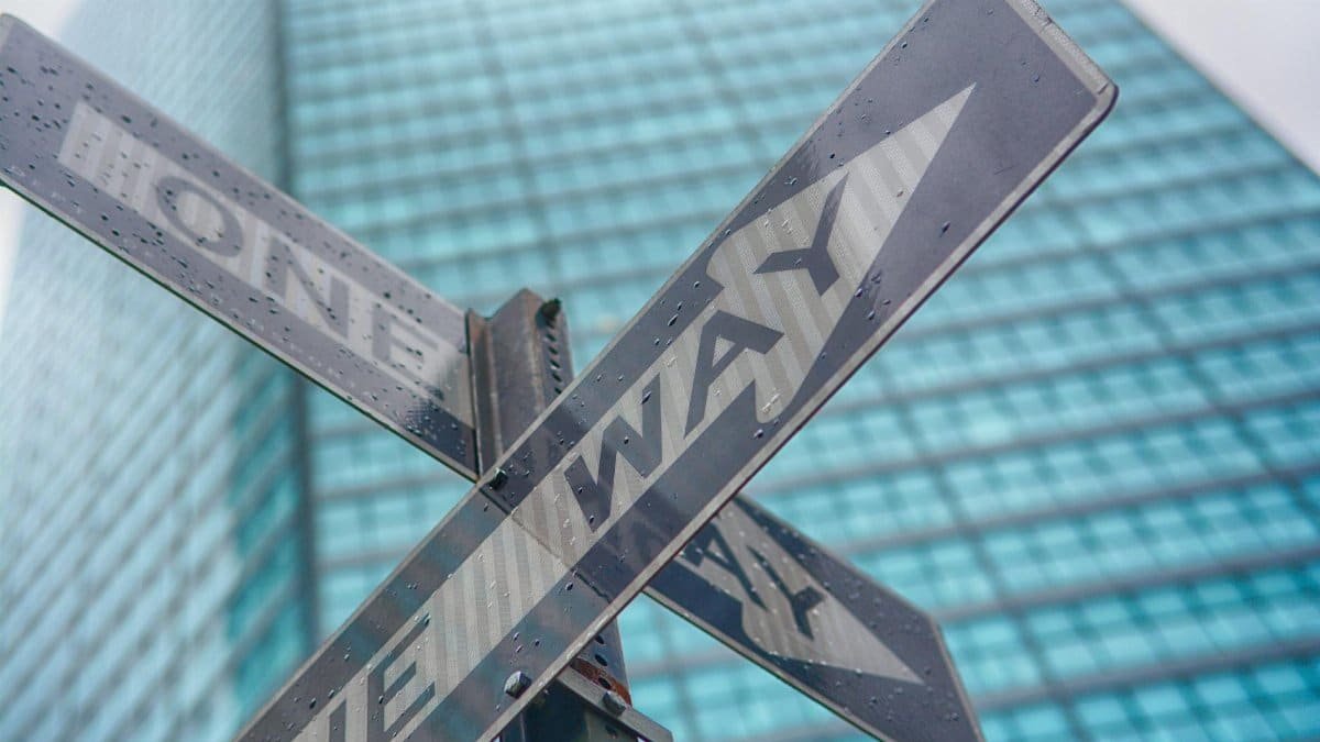 Close-up of a one way street sign in front of a skyscraper in New York City.