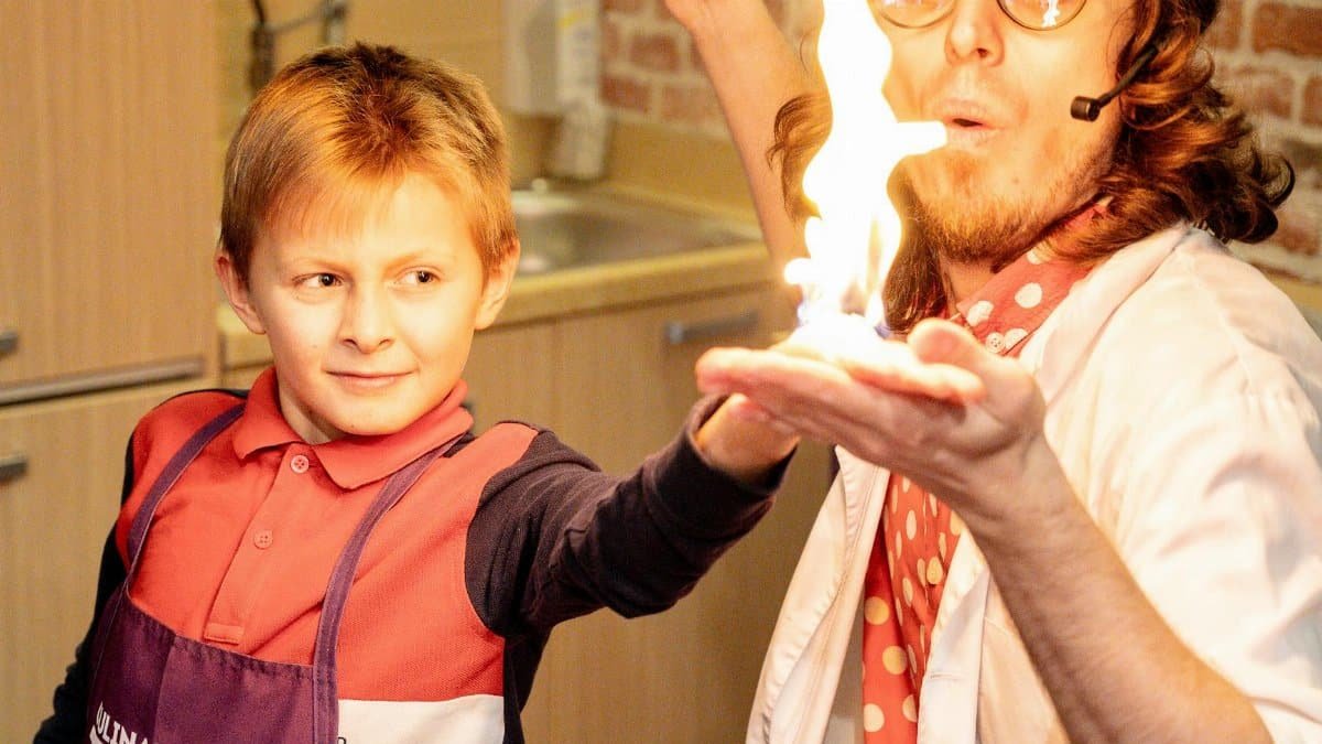 A playful science experiment with a man and child showcasing a fiery magic trick indoors.