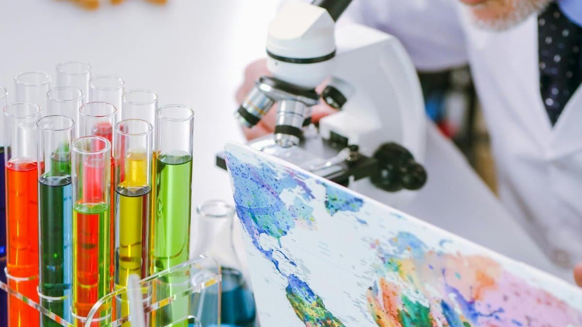 Scientist examining colorful liquids in test tubes using a microscope in a laboratory.