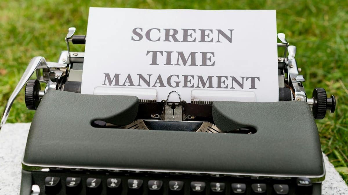 Retro typewriter displaying 'Screen Time Management' on paper outdoors.