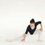 A ballerina gracefully performs a pose in a studio with a white background.