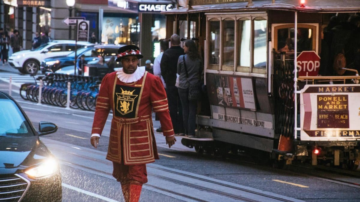 A costumed performer near a San Francisco cable car on a bustling street.