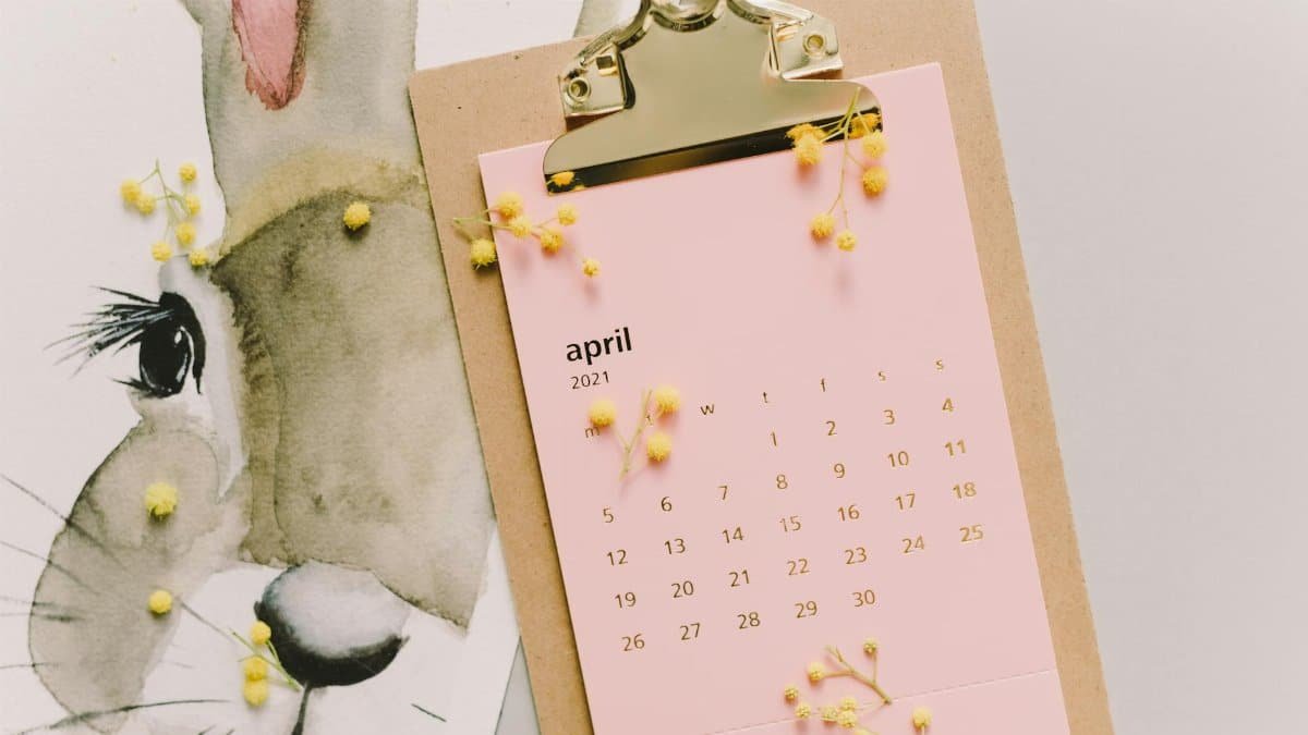 April 2021 calendar with watercolor bunny and mimosa flowers on clipboard.