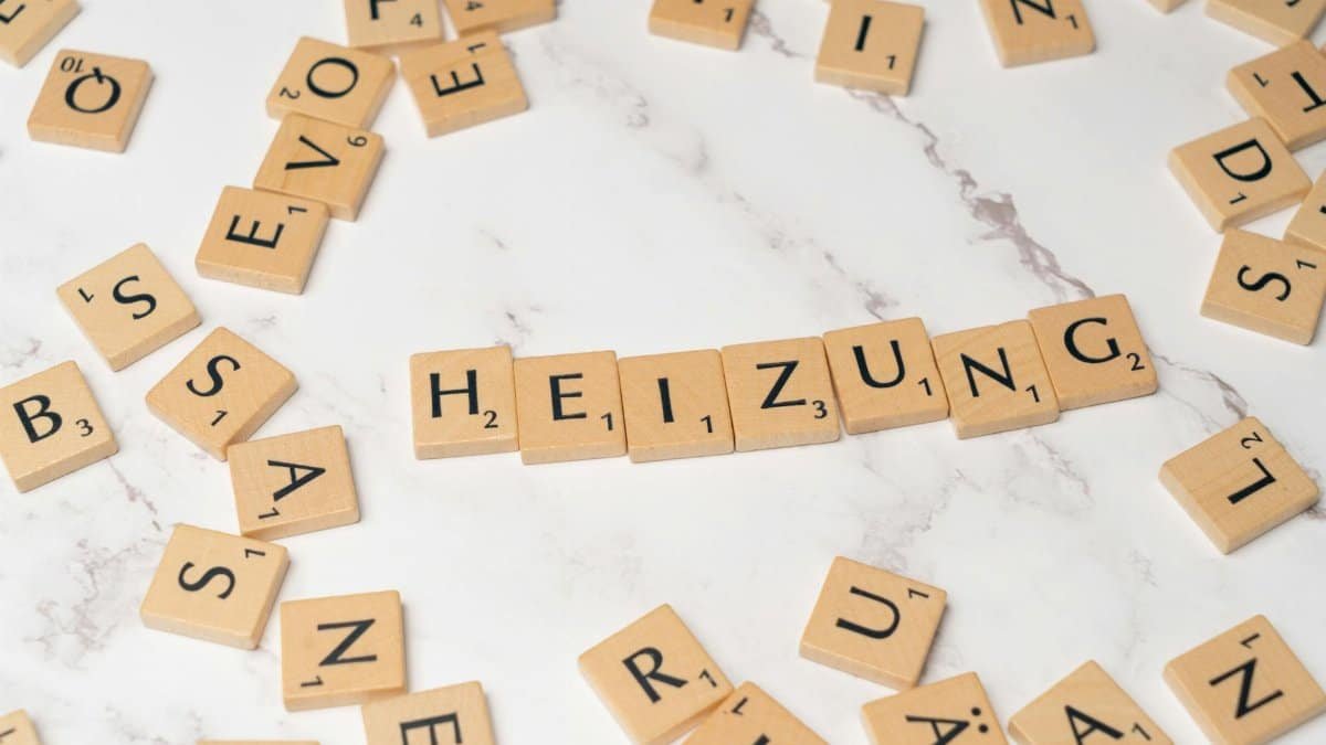 Scrabble tiles spelling 'Heizung' surrounded by scattered tiles on a marble surface.