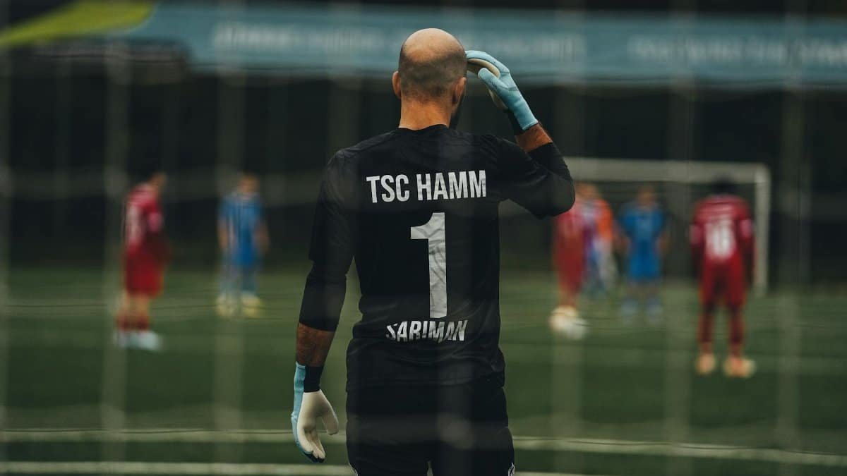 A soccer goalkeeper stands ready for a penalty kick on a field.