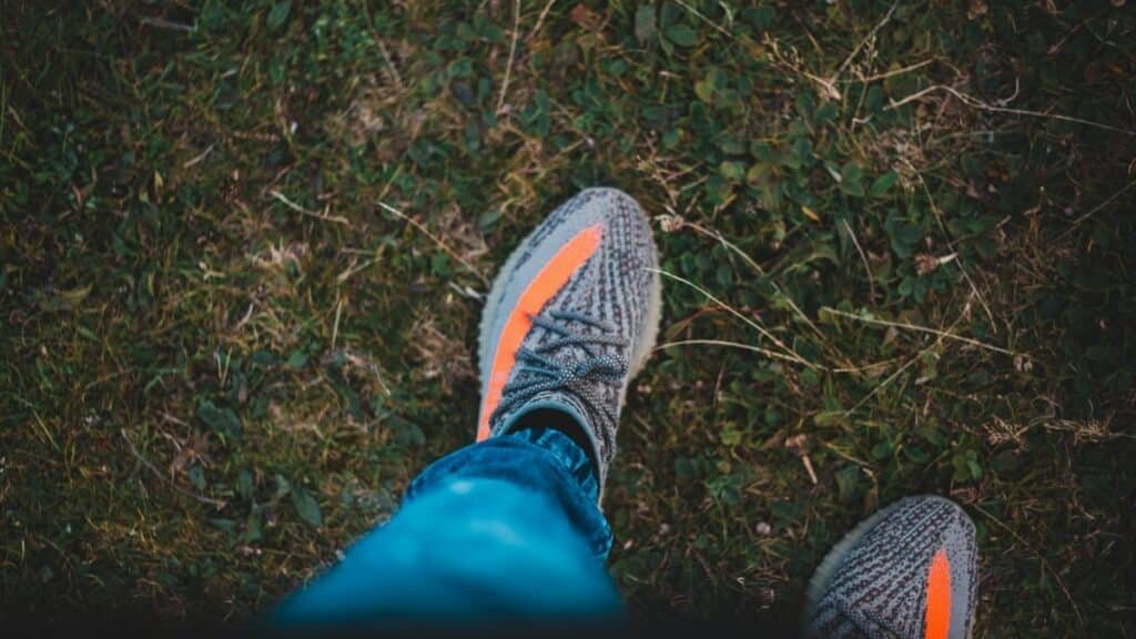 Top view of crop unrecognizable tourist in stylish footwear with stripes standing on lawn