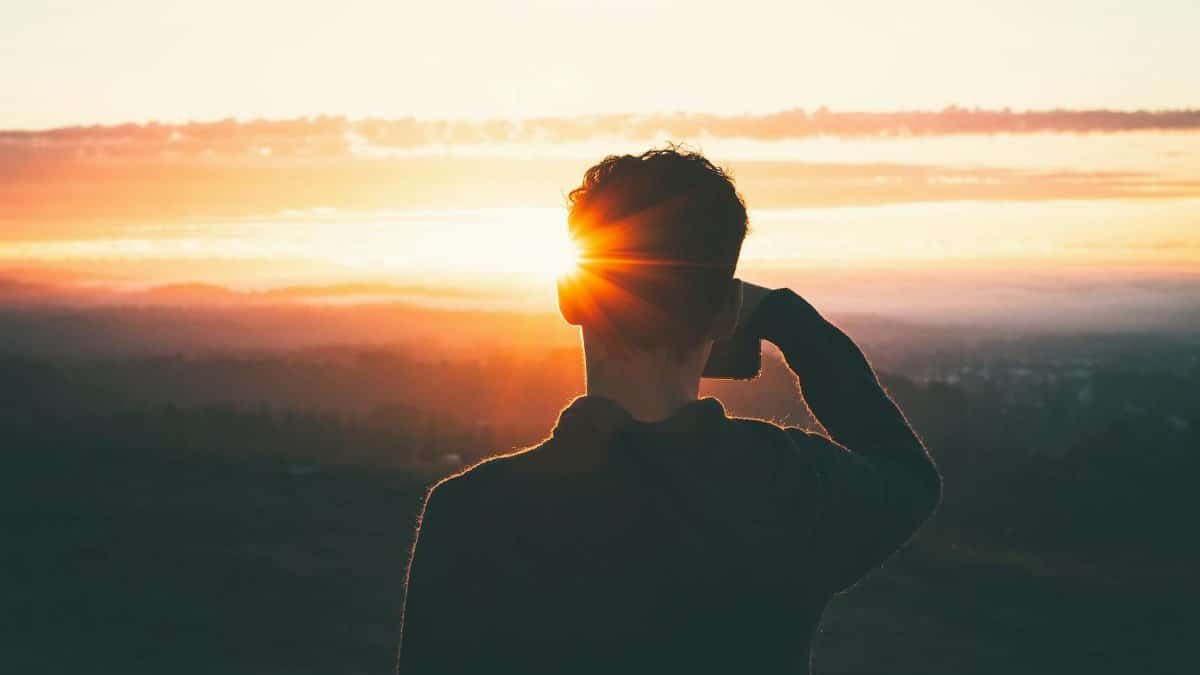 Silhouette of a man at sunrise, capturing the vibrant sky and serene landscape