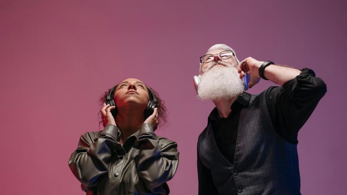 Two adults enjoying music with wireless headphones in a studio setting, evoking creativity and innovation.