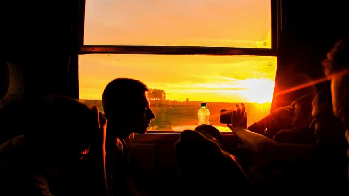 Silhouette of people on a train capturing a vivid sunset through a window.