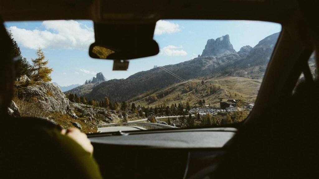 Experience the breathtaking view of the Dolomites through a car windshield, highlighting the adventure of a road trip.
