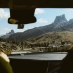 Experience the breathtaking view of the Dolomites through a car windshield, highlighting the adventure of a road trip.