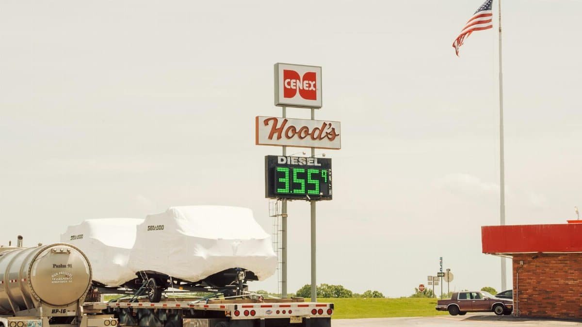 A rural gas station showing diesel price, featuring trucks and American flag.
