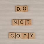 Close-up of wooden tiles spelling 'Do Not Copy' on a textured surface.