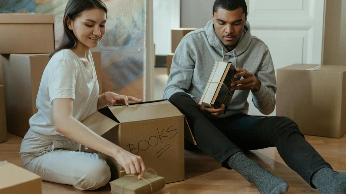 Young couple unpacking and organizing books in their new home.