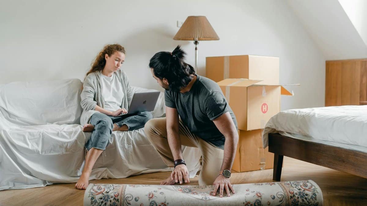 A couple relaxes while unpacking in their new apartment, creating a cozy home environment.