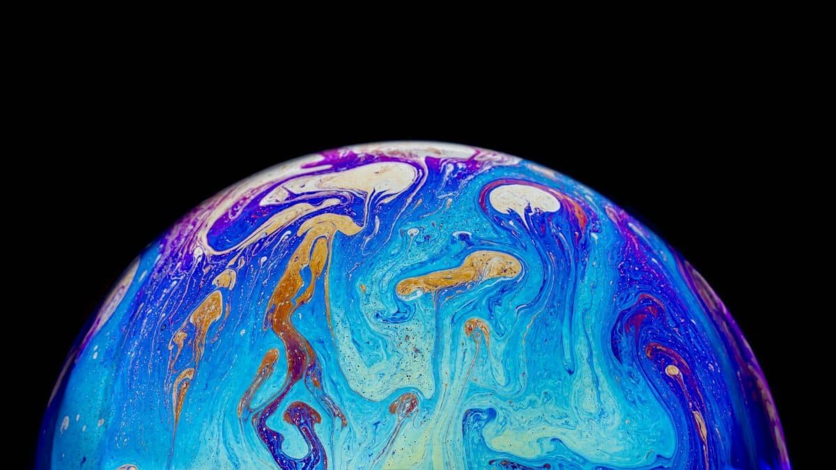 Stunning close-up of vibrant soap bubble with swirling iridescent colors against a black background.