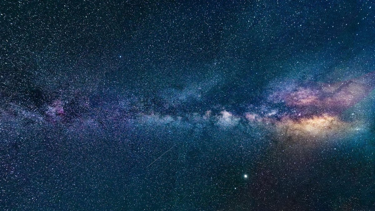 Capture of the Milky Way galaxy stretching across the dark night sky, filled with stars.