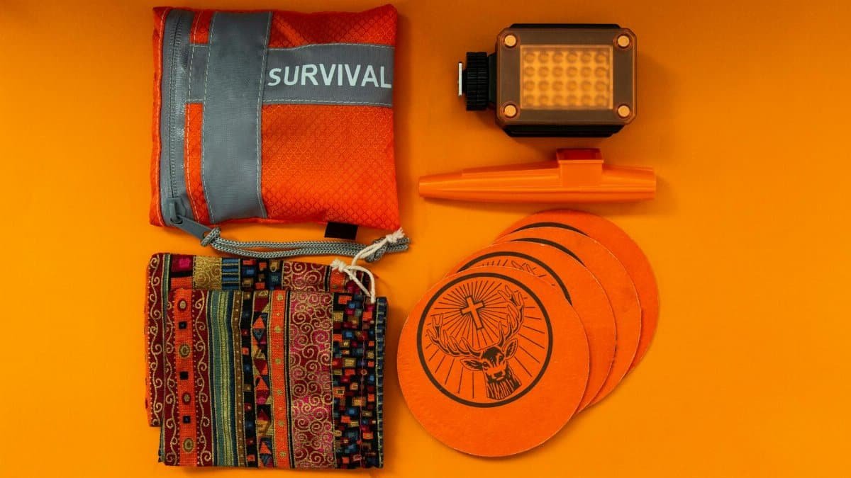 Flat lay of colorful survival kit items on orange background, showcasing vibrant essentials.