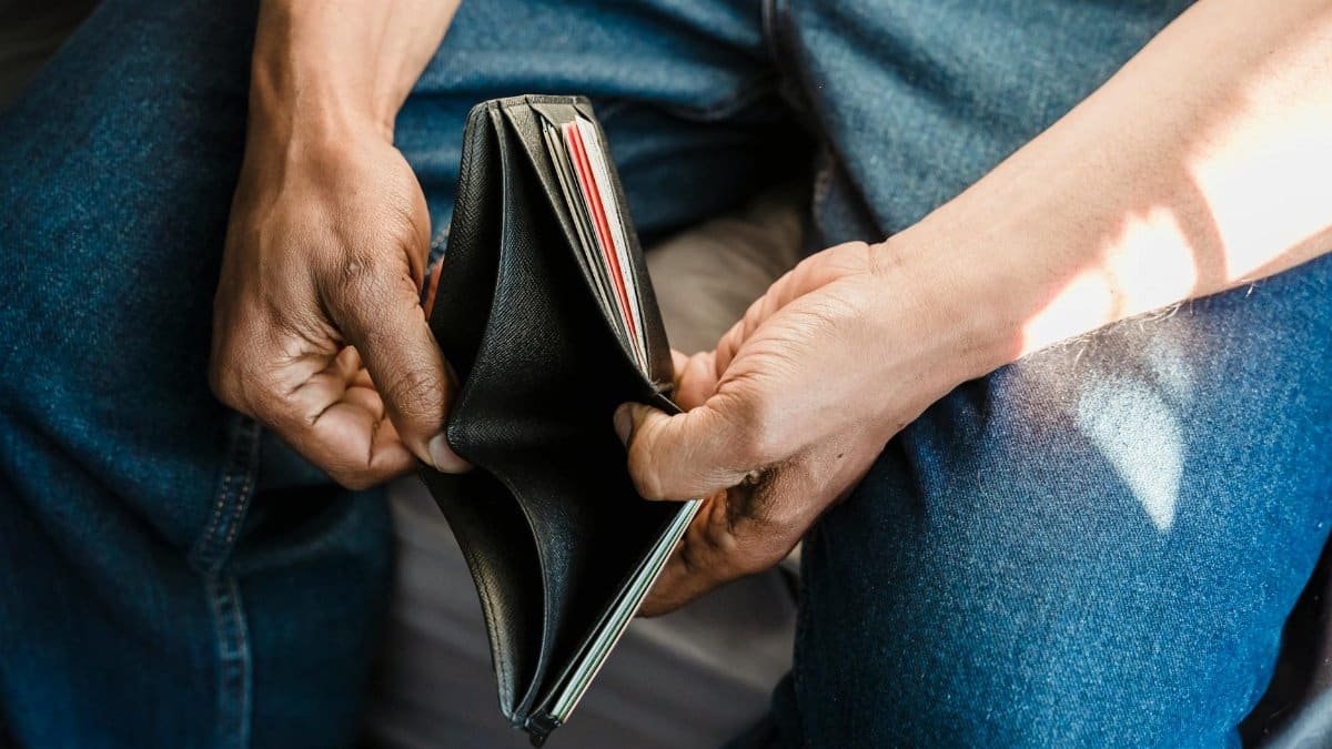 Close-up of a man holding an empty wallet, symbolizing financial crisis and hardship.