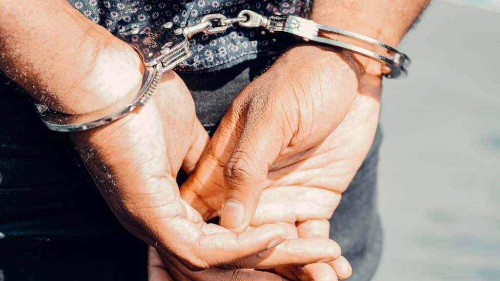 Close-up of an adult male's hands in handcuffs, symbolizing law enforcement and justice.