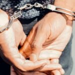 Close-up of an adult male's hands in handcuffs, symbolizing law enforcement and justice.