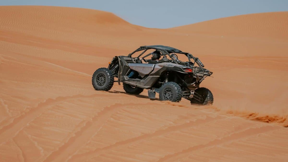 ATV racing through sandy desert dunes under clear skies. Perfect for adventure enthusiasts.